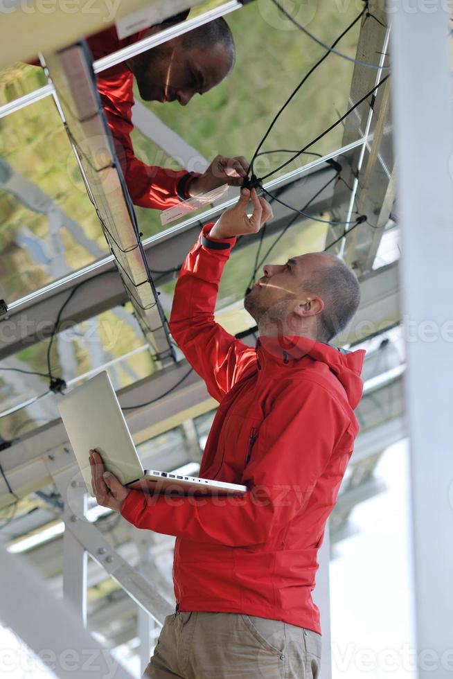 engineer using laptop at solar panels plant field photo