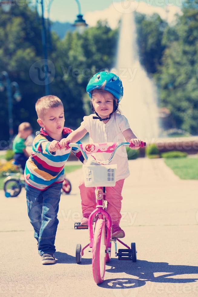 Boy and girl in park learning to ride a bike photo