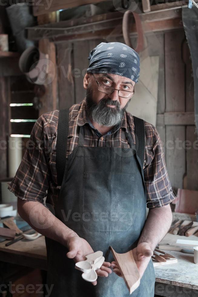 Spoon master in his workshop with wooden products and tools photo