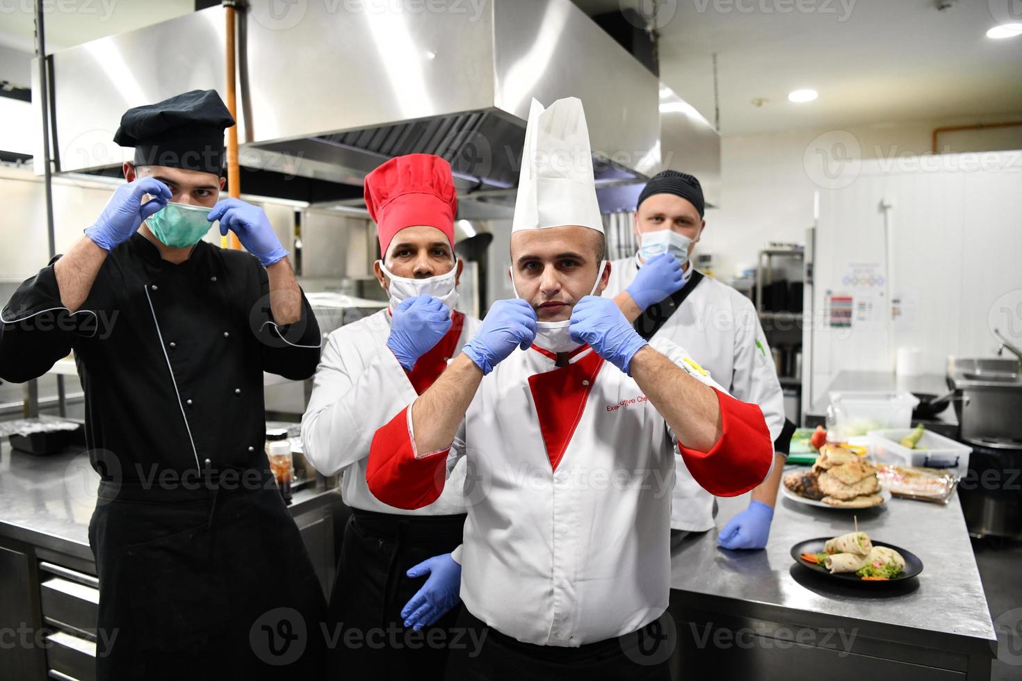 group chefs standing together in the kitchen at restaurant wearing protective medical mask and gloves in coronavirus new normal concept photo