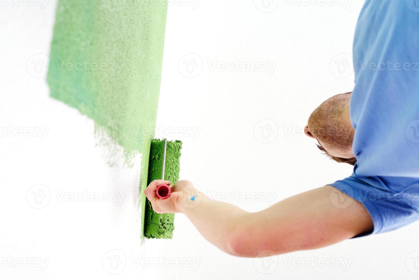 handsome young man paint white wall in color photo