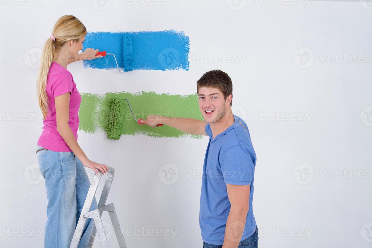 happy couple paint wall at new home photo