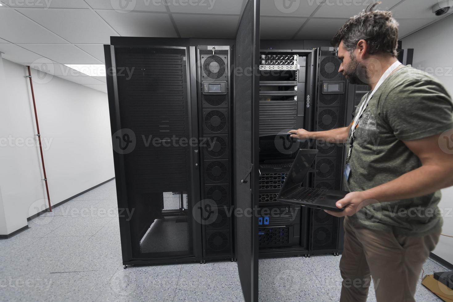 Data Center Engineer Usaing Keyboard on a Supercomputer Server Room Specialist Facility with Male System Administrator photo