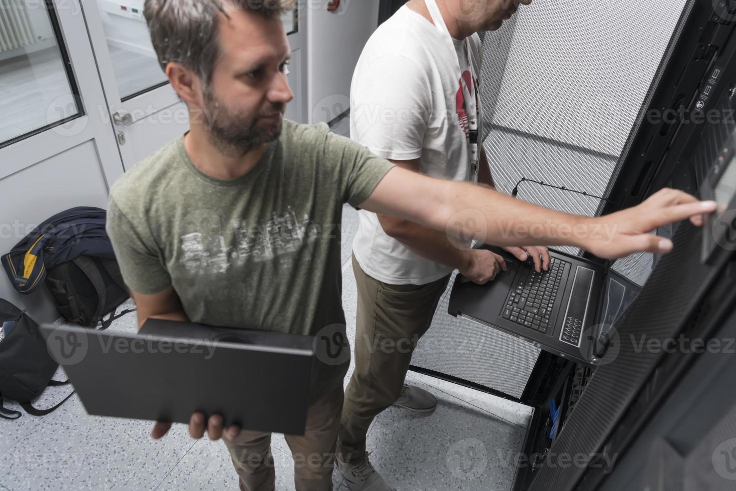 Technicians team updating hardware inspecting system performance in super computer server room or cryptocurrency mining farm. photo