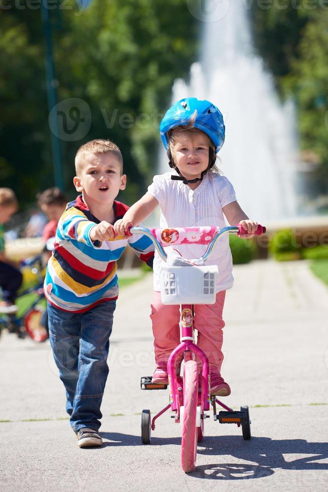 Boy and girl in park learning to ride a bike photo