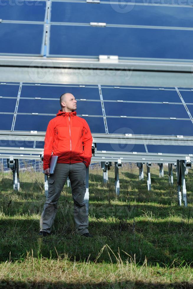 engineer using laptop at solar panels plant field photo