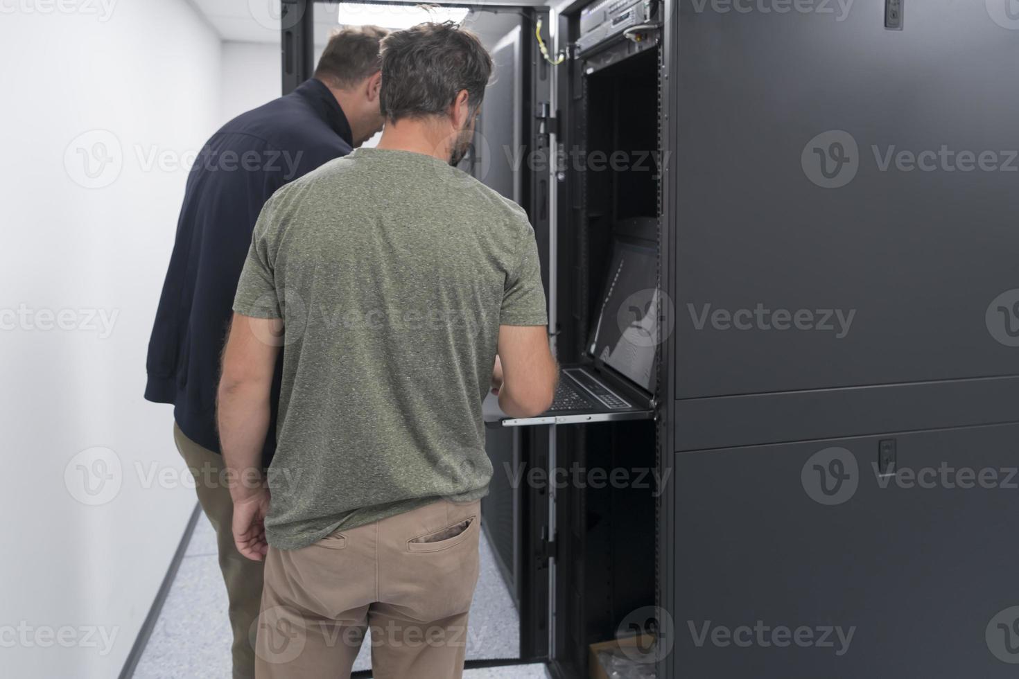 Technicians team updating hardware inspecting system performance in super computer server room or cryptocurrency mining farm. photo