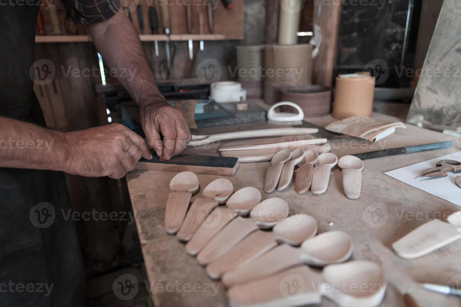 Hands carving spoon from wood, working with chisel close up. Wooden workshop. Process of making wooden spoon photo