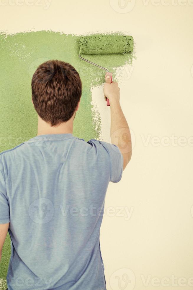 handsome young man paint white wall in color photo