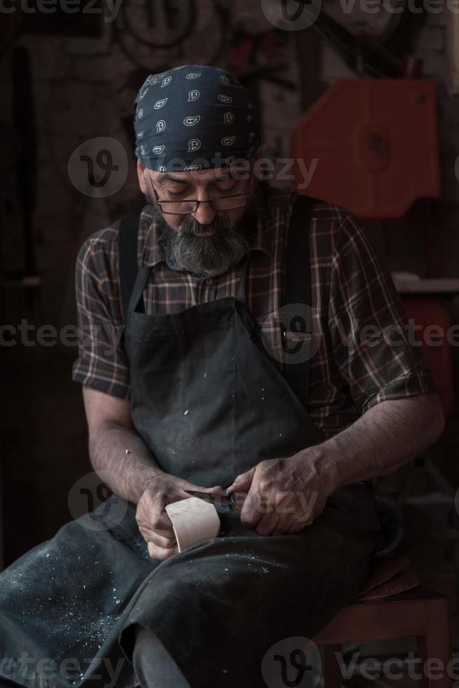 Spoon craft master in his workshop with handmade wooden products and tools working photo