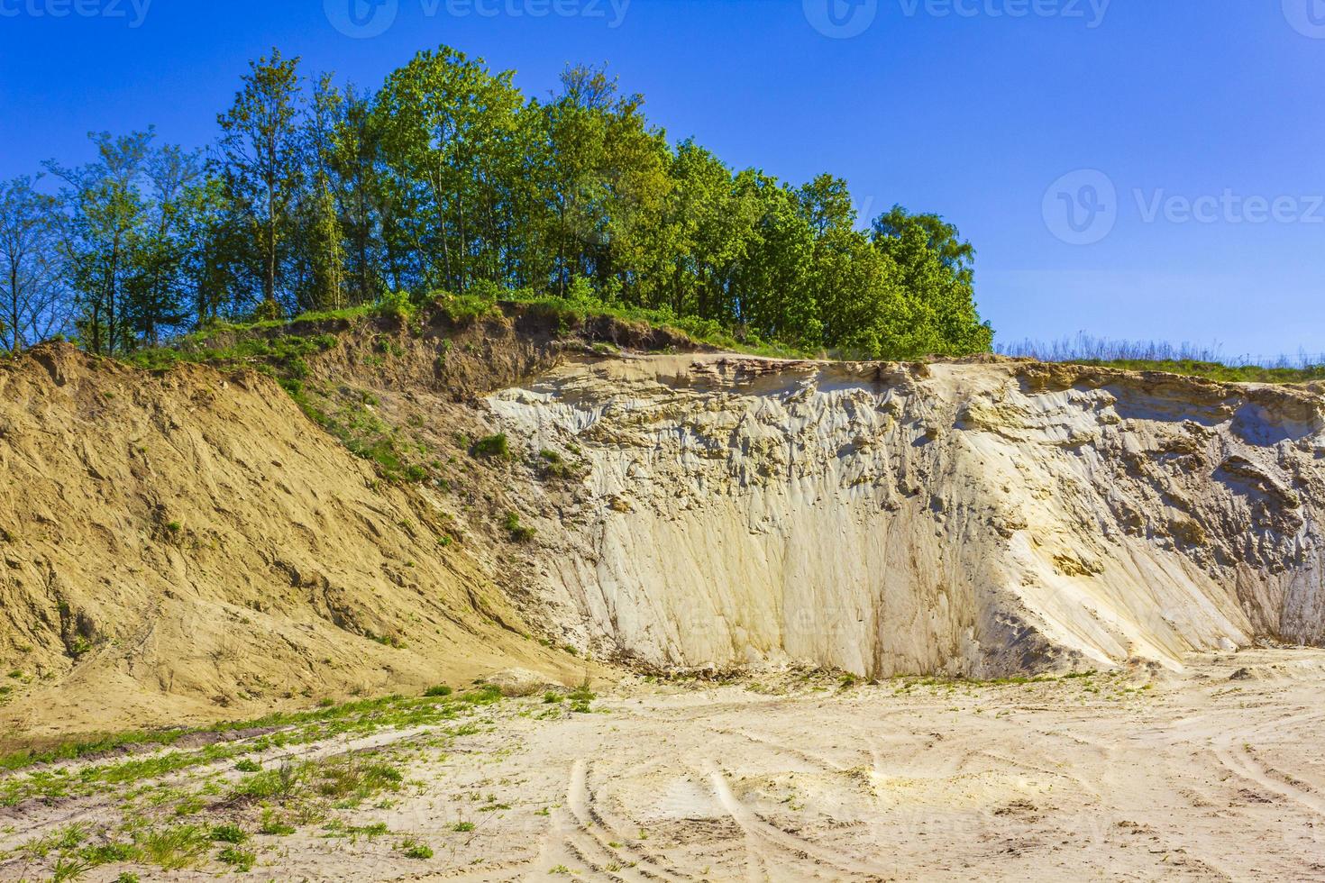 Excavated sand mountains and rubble piles quarry lake dredging pond. photo