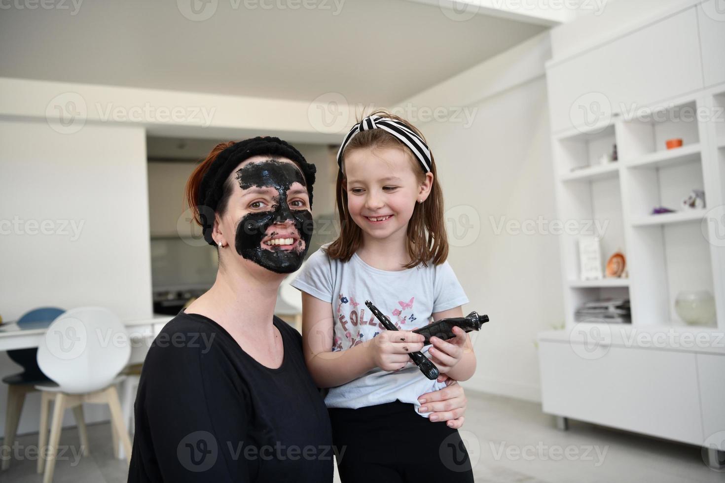 mother and daughter at home making facial mask beauty treatment photo
