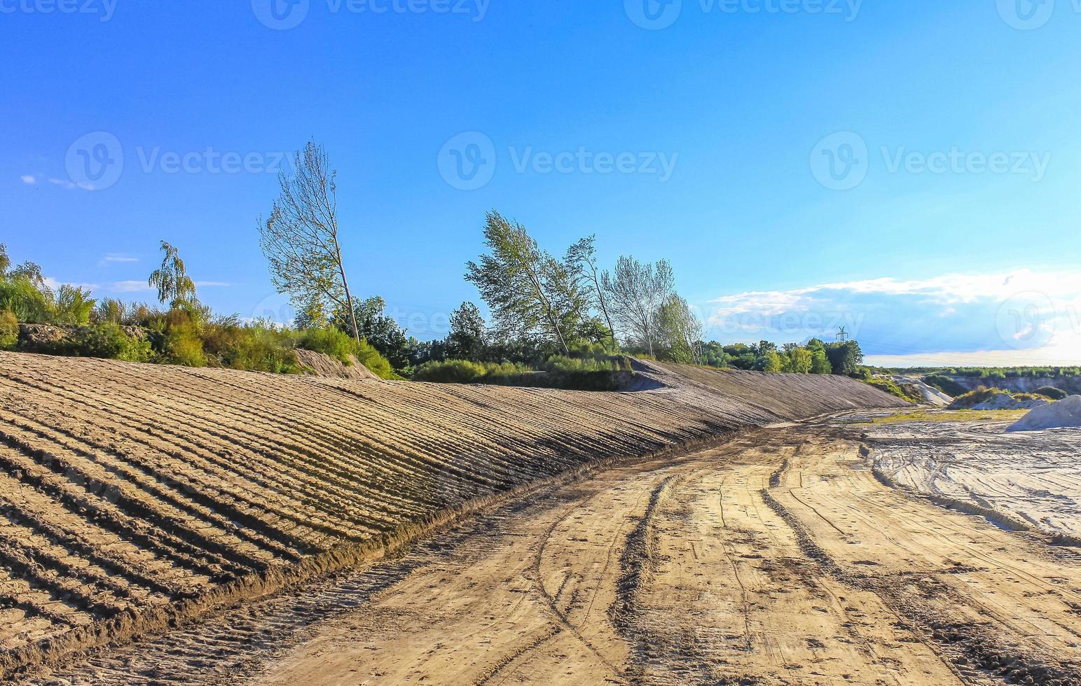 Excavated sand mountains and rubble piles quarry lake dredging pond. photo