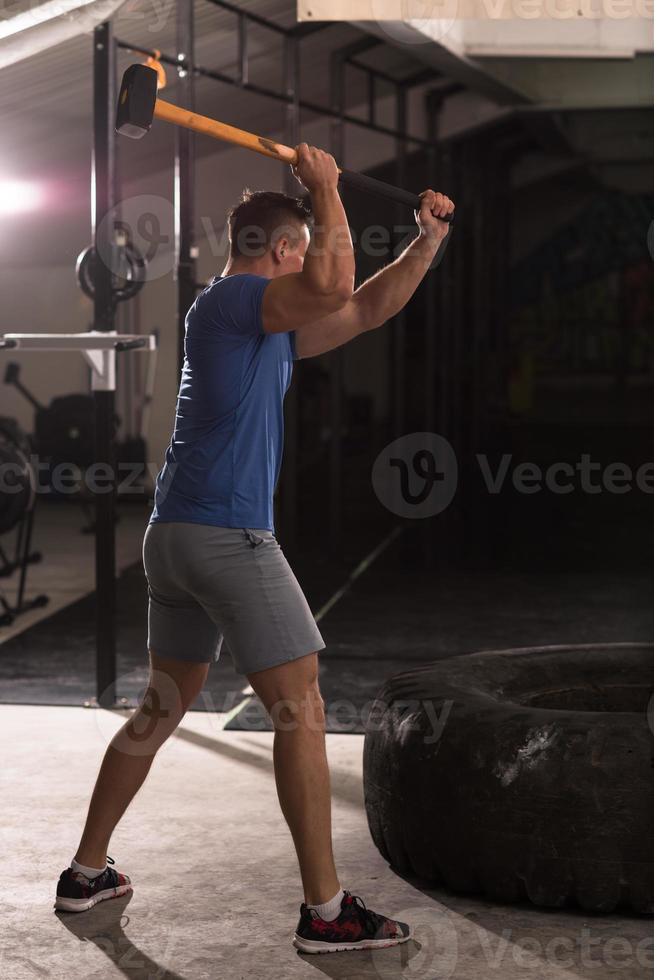 man workout with hammer and tractor tire photo