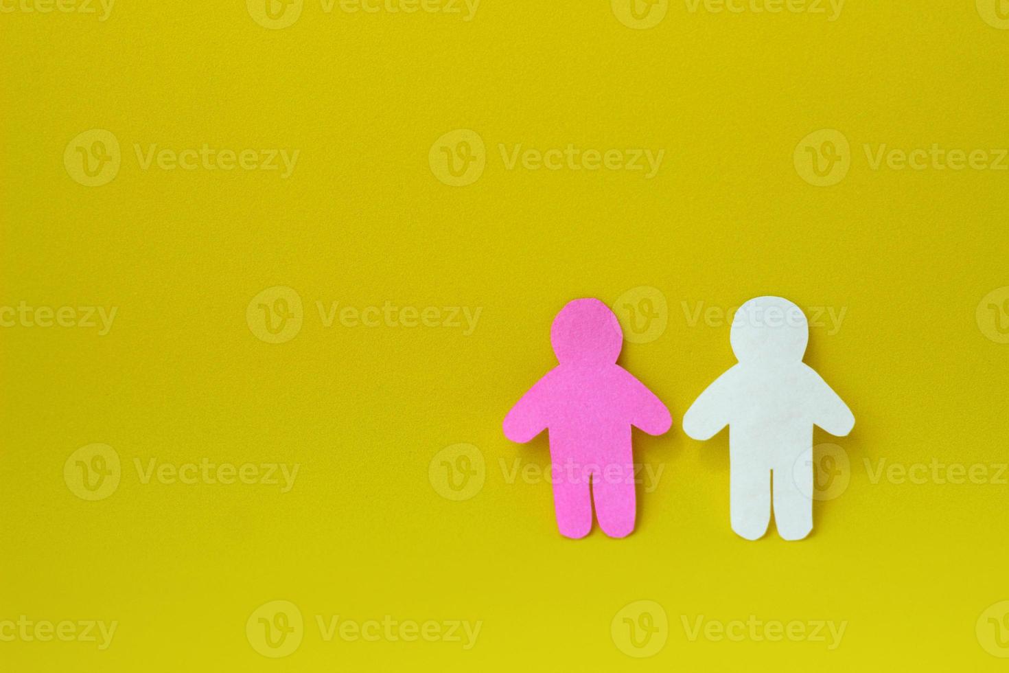 Two silhouettes of a people carved from white and pink paper on yellow background. On right side of photo with copy space. Concept of communication, relationships, love, teamwork