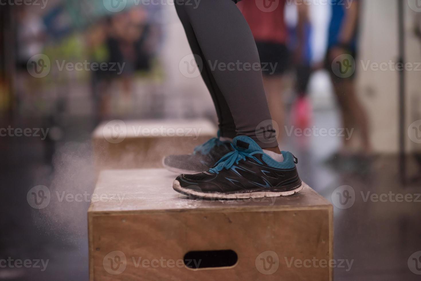 black woman is performing box jumps at gym photo