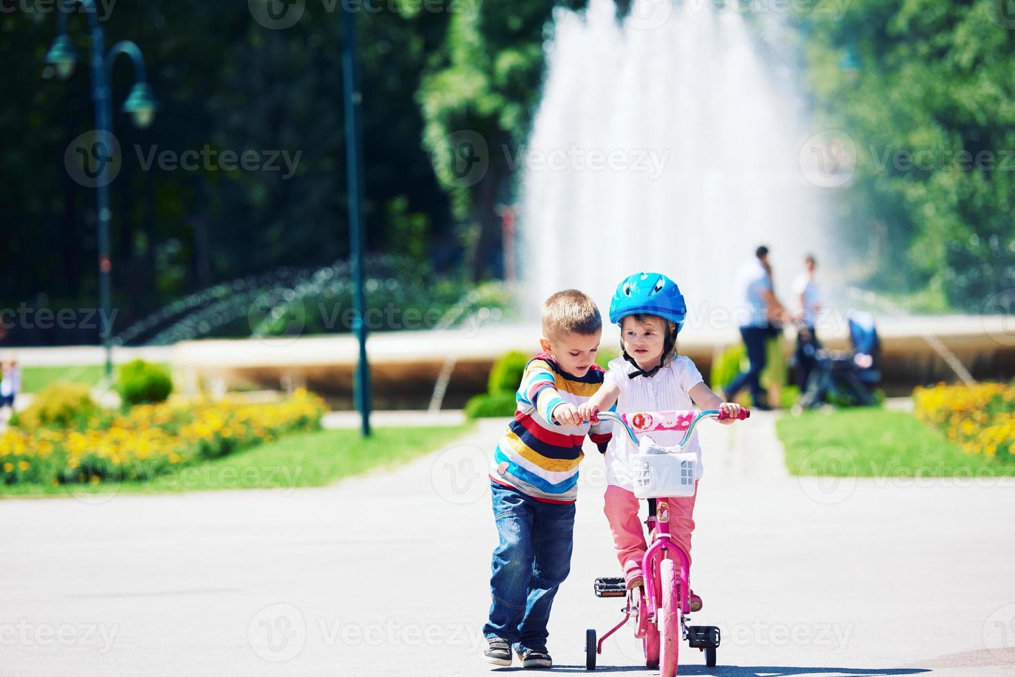 Boy and girl in park learning to ride a bike photo