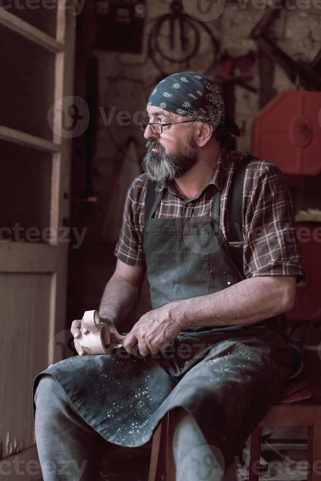 Spoon craft master in his workshop with handmade wooden products and tools working photo