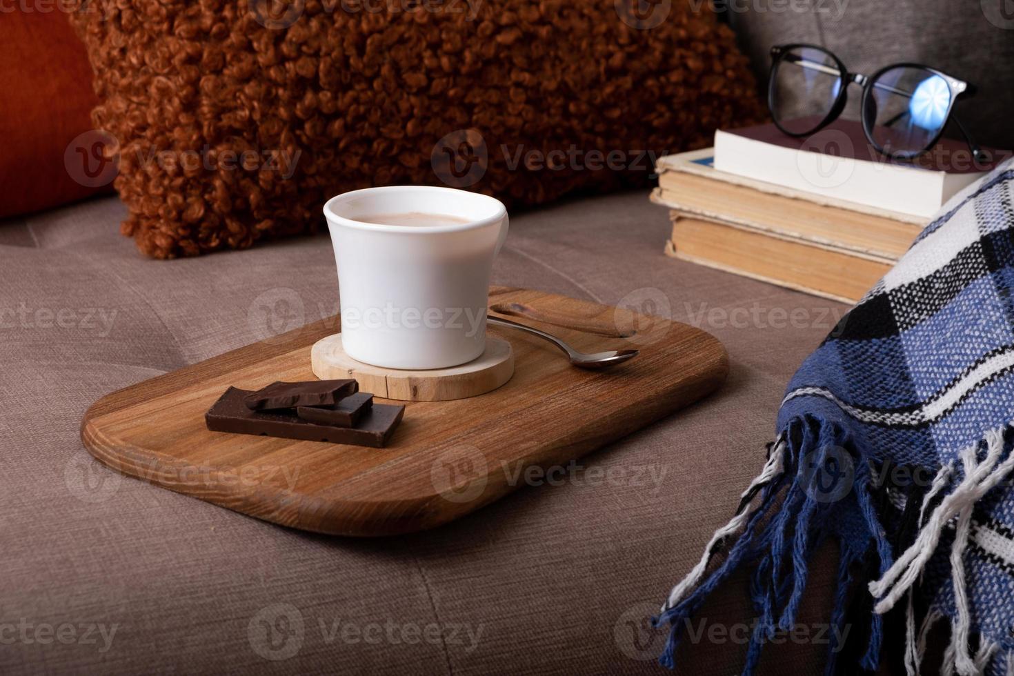 Autumn mood background with cup of cocoa, plaid and books on sofa. Hot drink in autumn concept photo