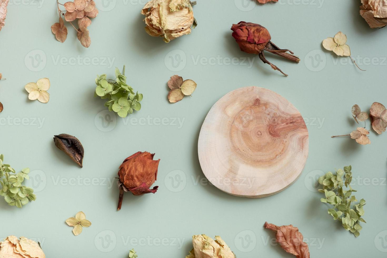 Saw podium or pedestal with pattern from dry hydrangea flowers, roses and petals on pastel green colored background. Top view, flat lay photo