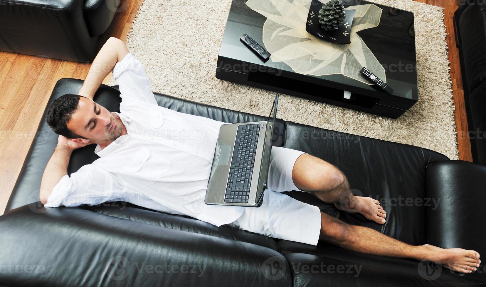 Portrait of a relaxed young guy using laptop at home photo