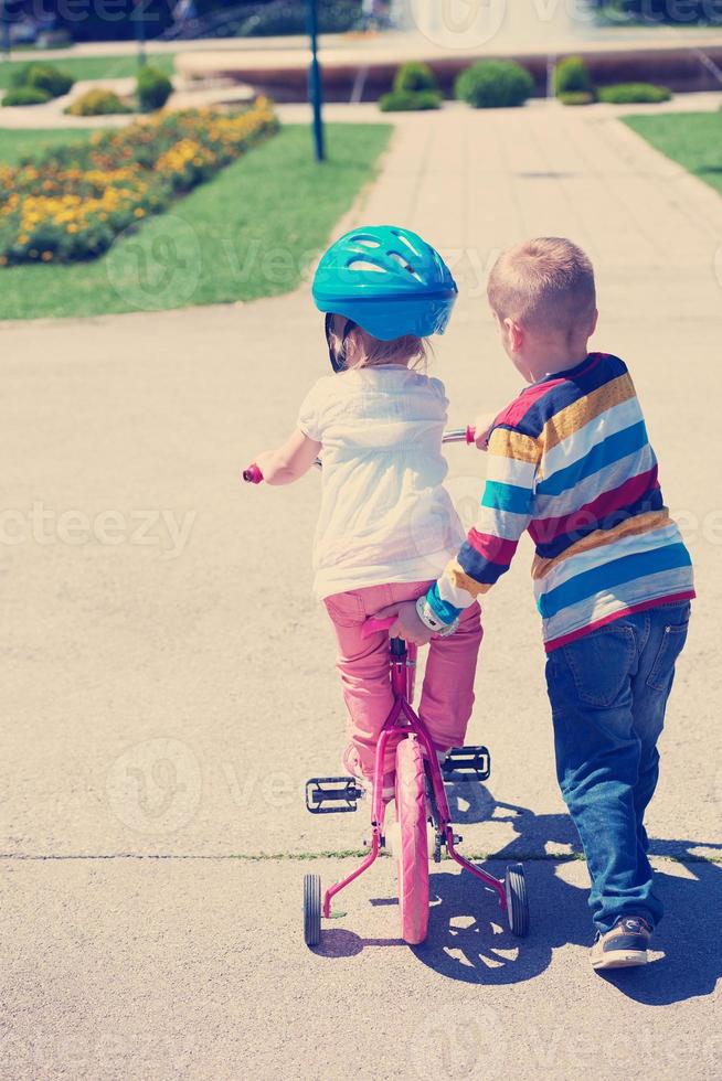 niño y niña en el parque aprendiendo a andar en bicicleta foto