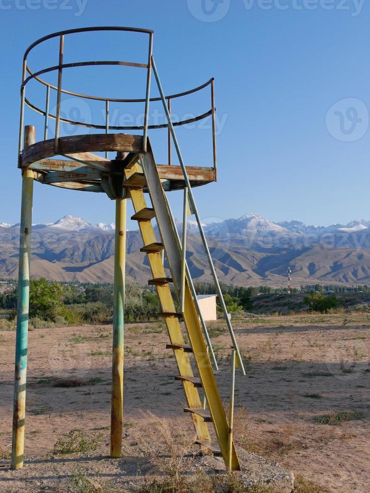 Structure on an abandoned playground in Kyrgyzstan with mountains in the background photo