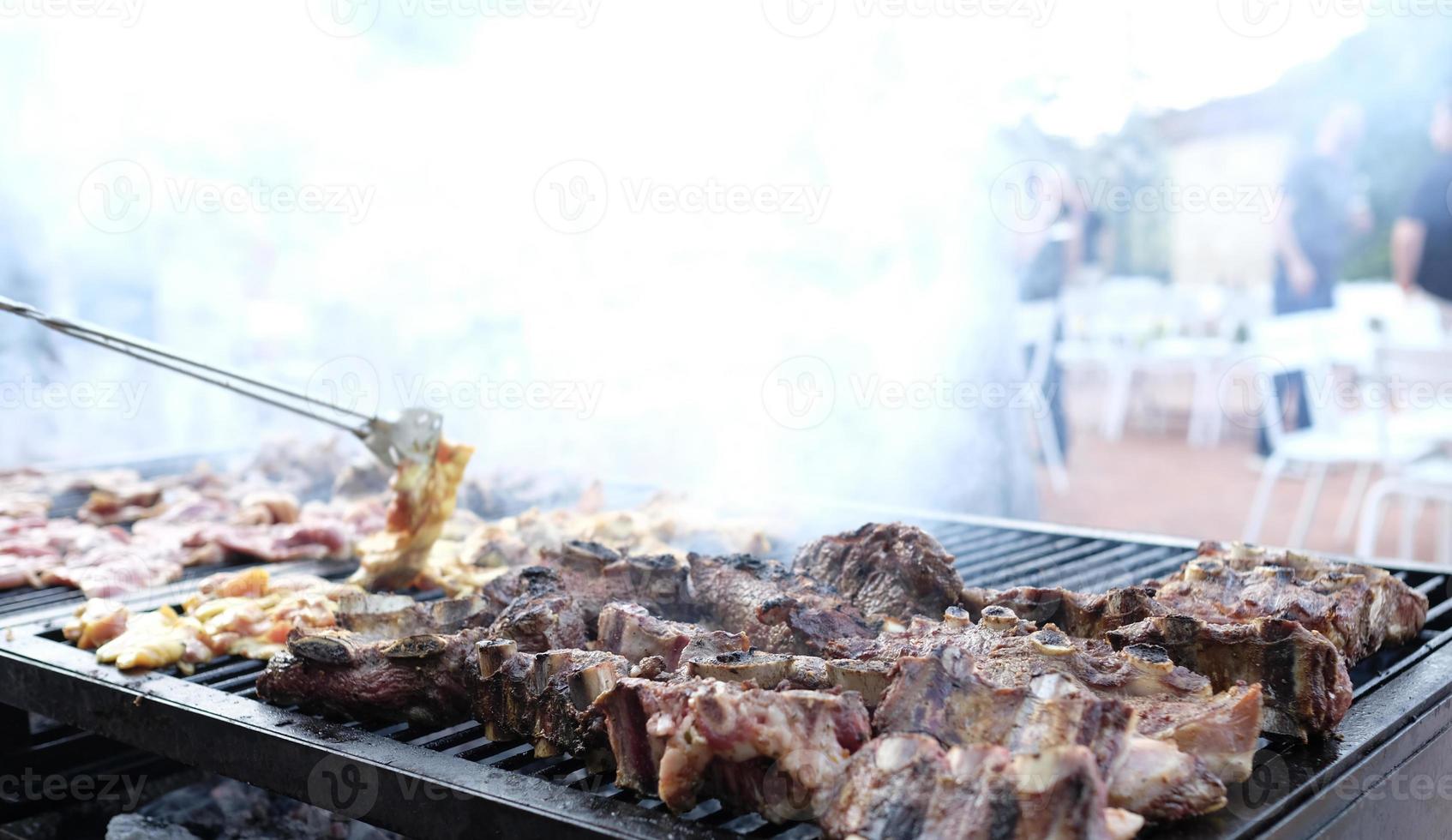 Smoking barbecue grill with numerous pieces of meat on it photo