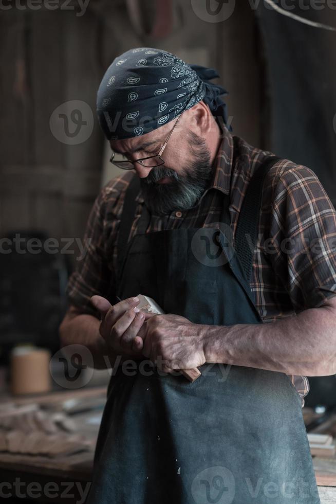 Spoon master in his workshop with wooden products and tools photo