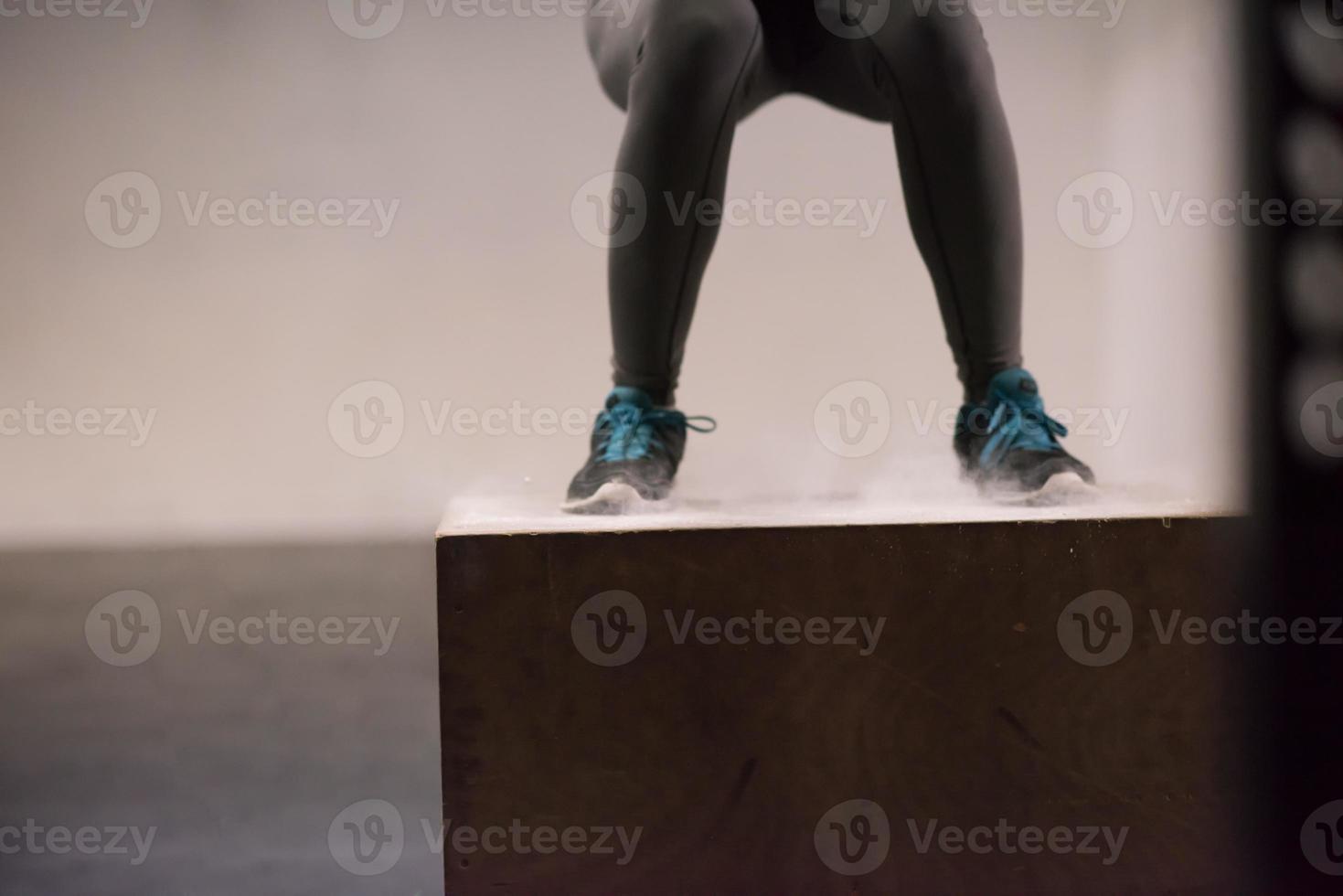 black woman is performing box jumps at gym photo