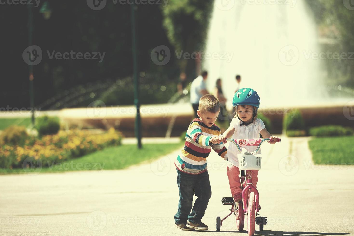 Boy and girl in park learning to ride a bike photo