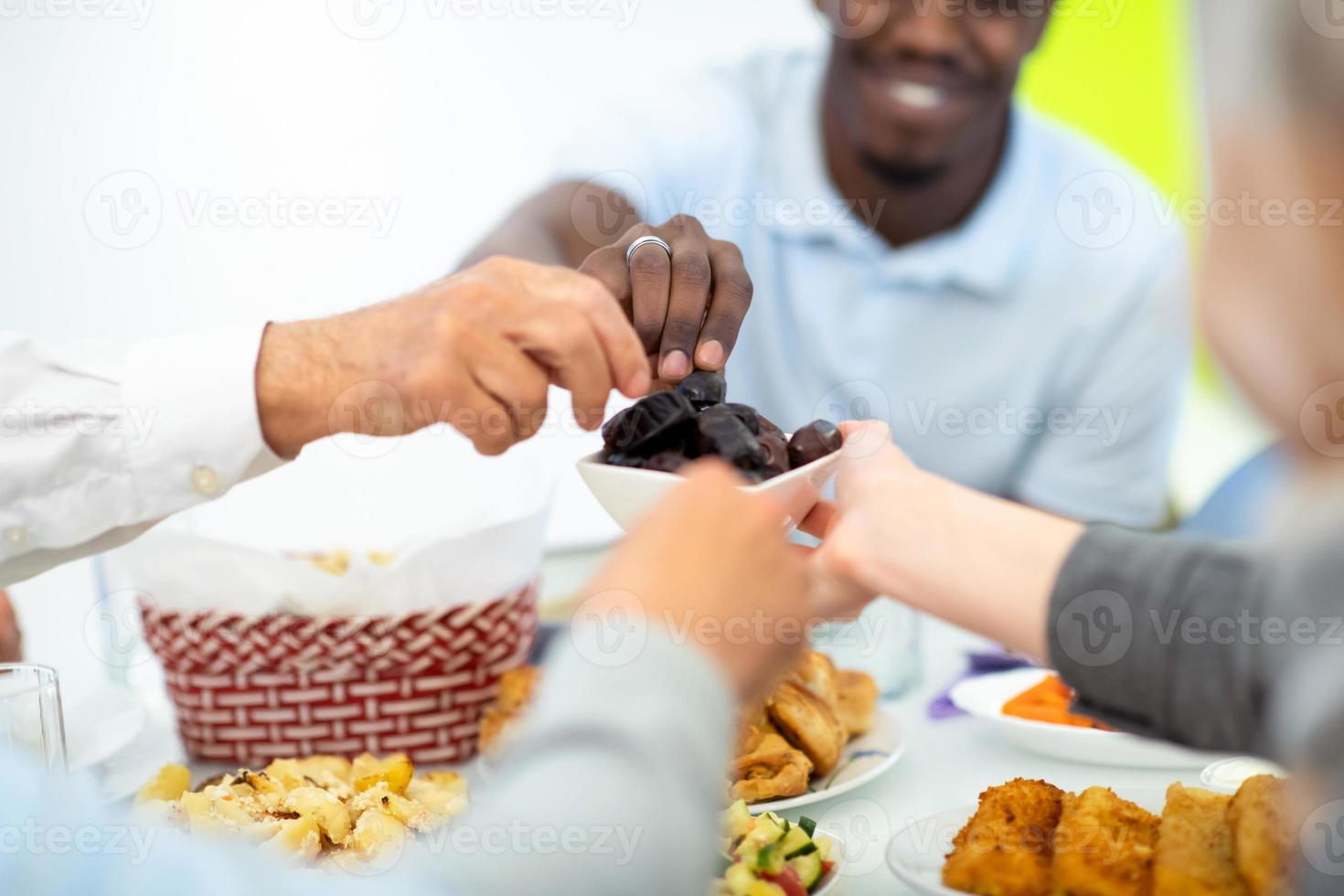 familia musulmana multiétnica moderna compartiendo un cuenco de dátiles foto