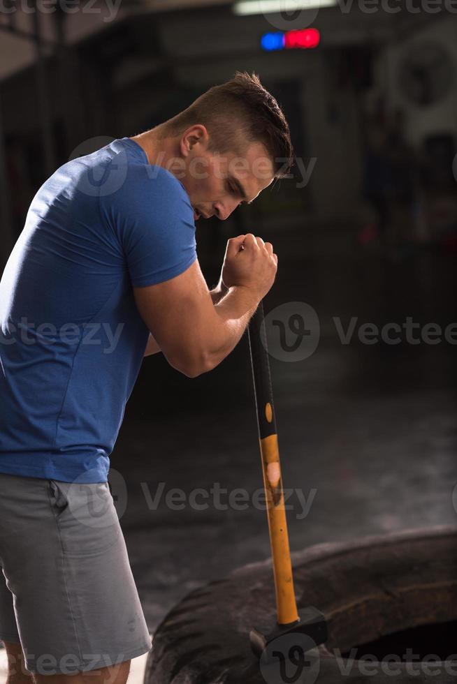 entrenamiento de hombre con martillo y neumático de tractor foto