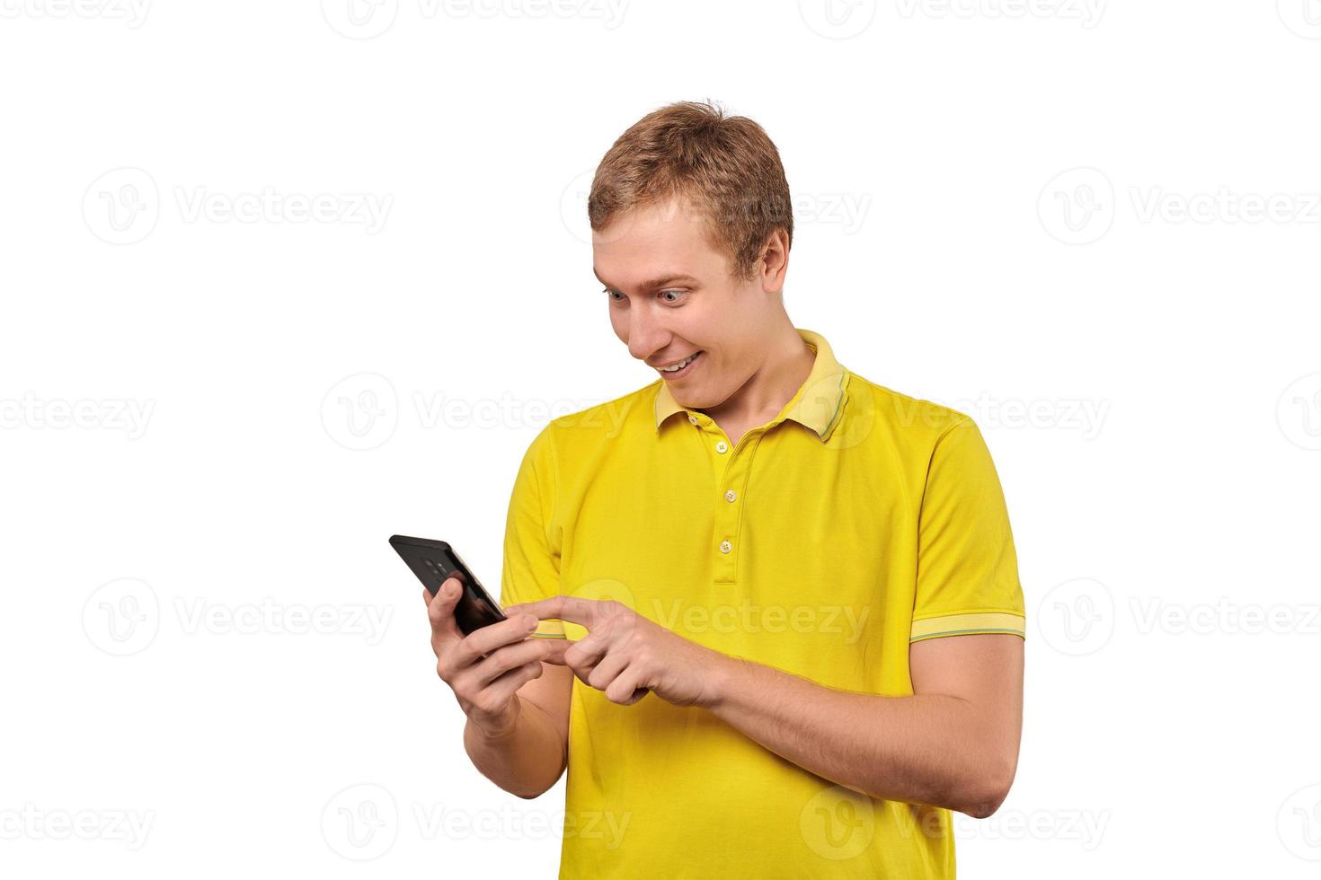 Surprised young man with smartphone, funny guy holding phone isolated on white background photo
