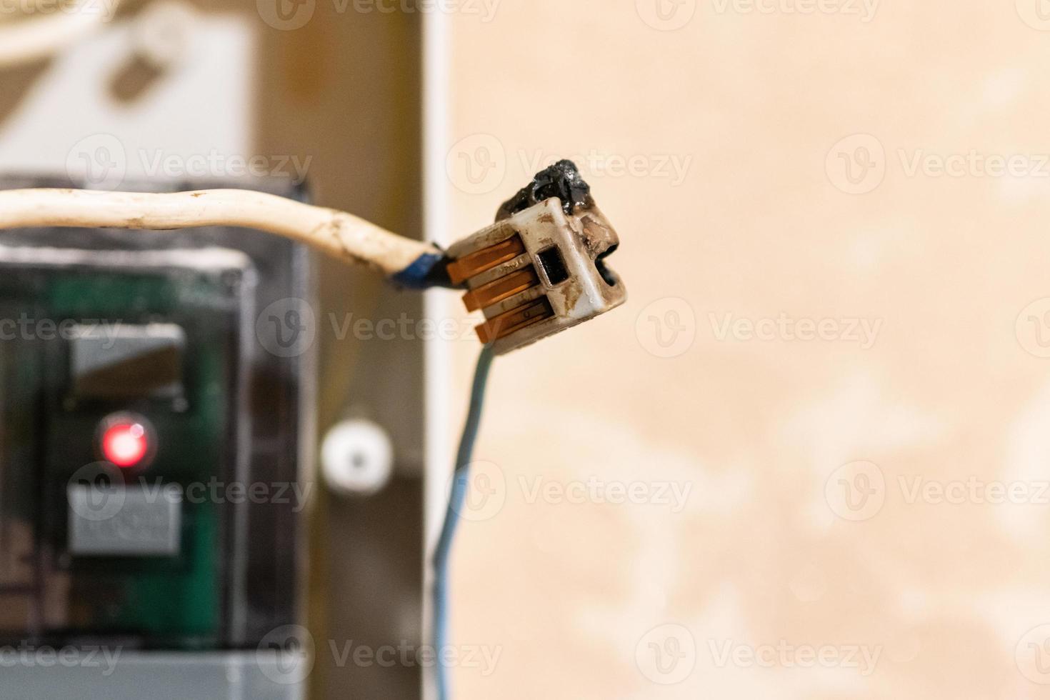 Burned wire, splicing connector, electrical terminal block of nonflammable, fireproof material. Faulty wiring or negligent electrical work. Dangerous short circuit accident. photo