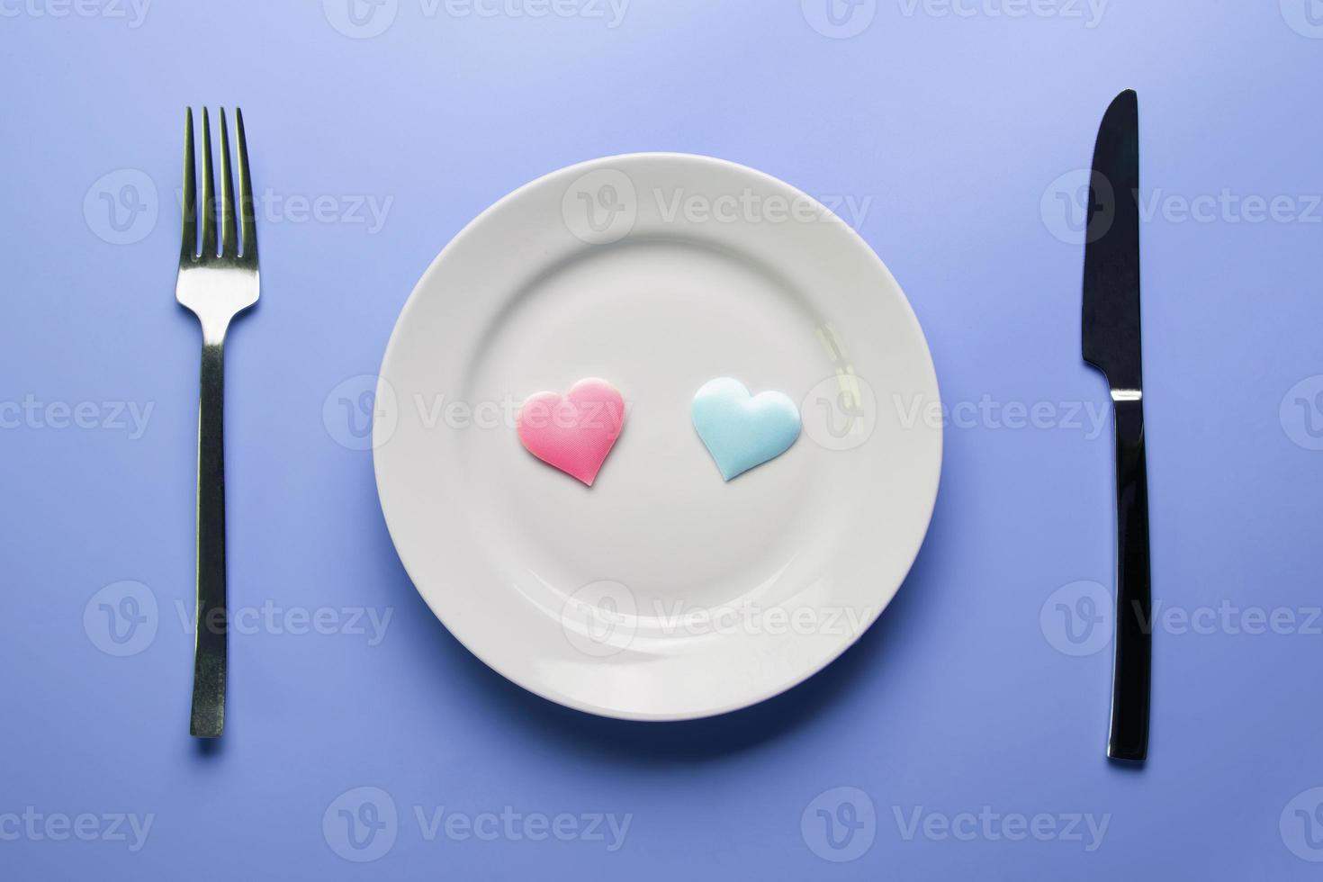 Two hearts in plate with cutlery. Romantic dinner in restaurant concept. Meeting of lovers at wedding reception. photo