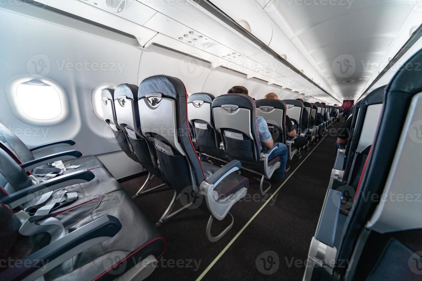 Airplane cabin seats with passengers. Economy class of new cheapest low-cost airlines. Travel trip to another country. Turbulence in flight. photo