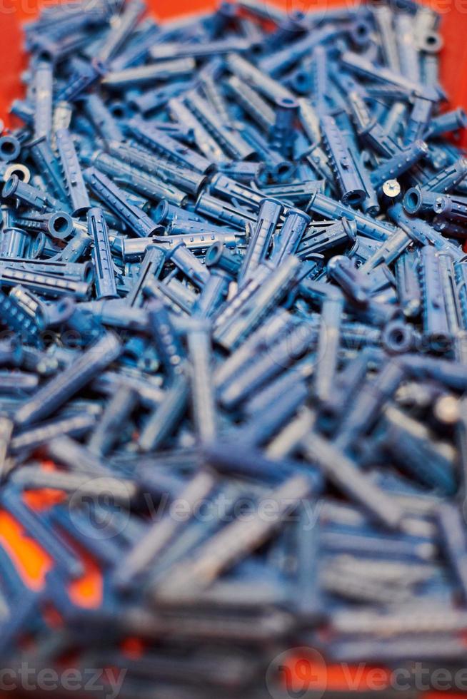 Plastic blue dowels on red background, wall plugs for fixation and installation, close up, top view photo