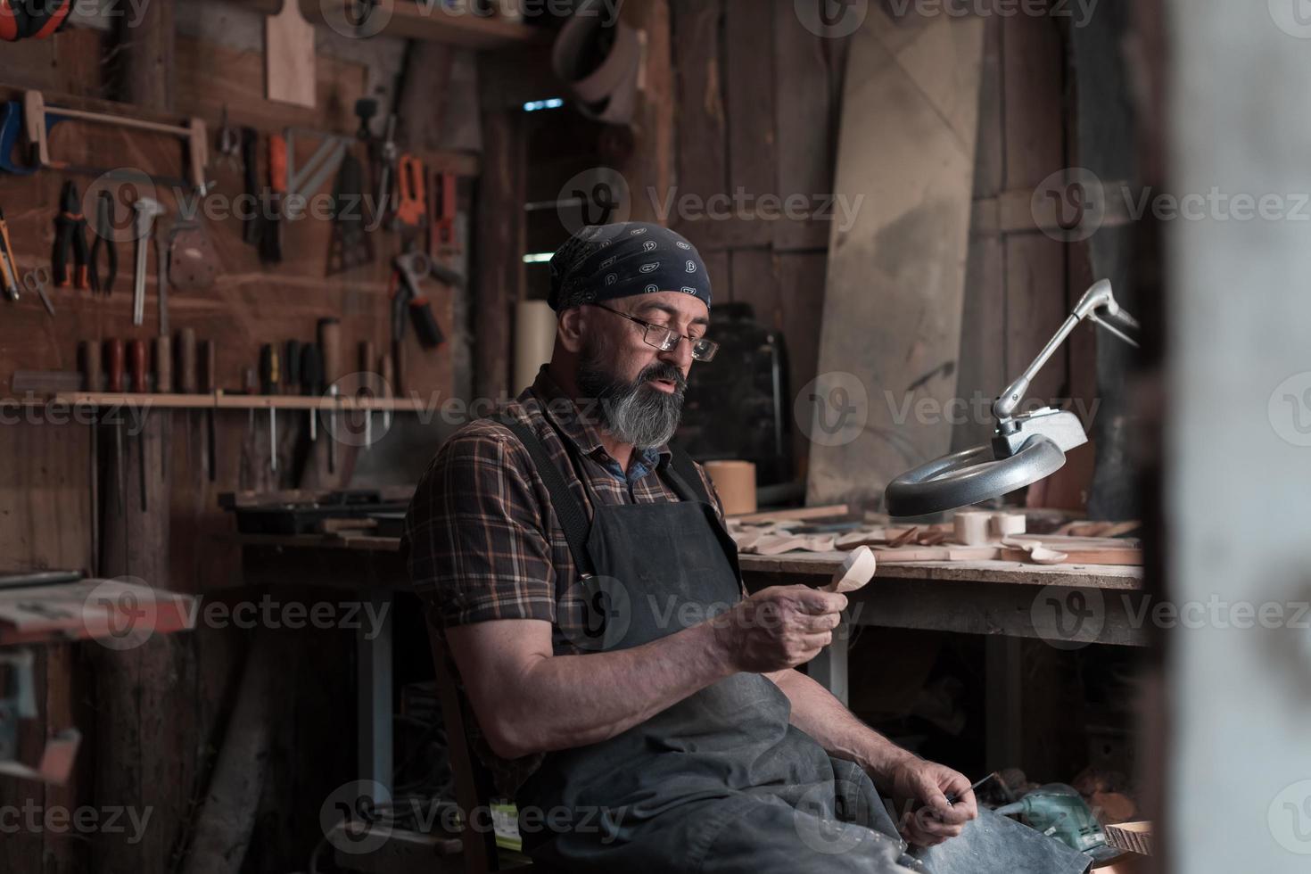 Spoon master in his workshop with wooden products and tools photo