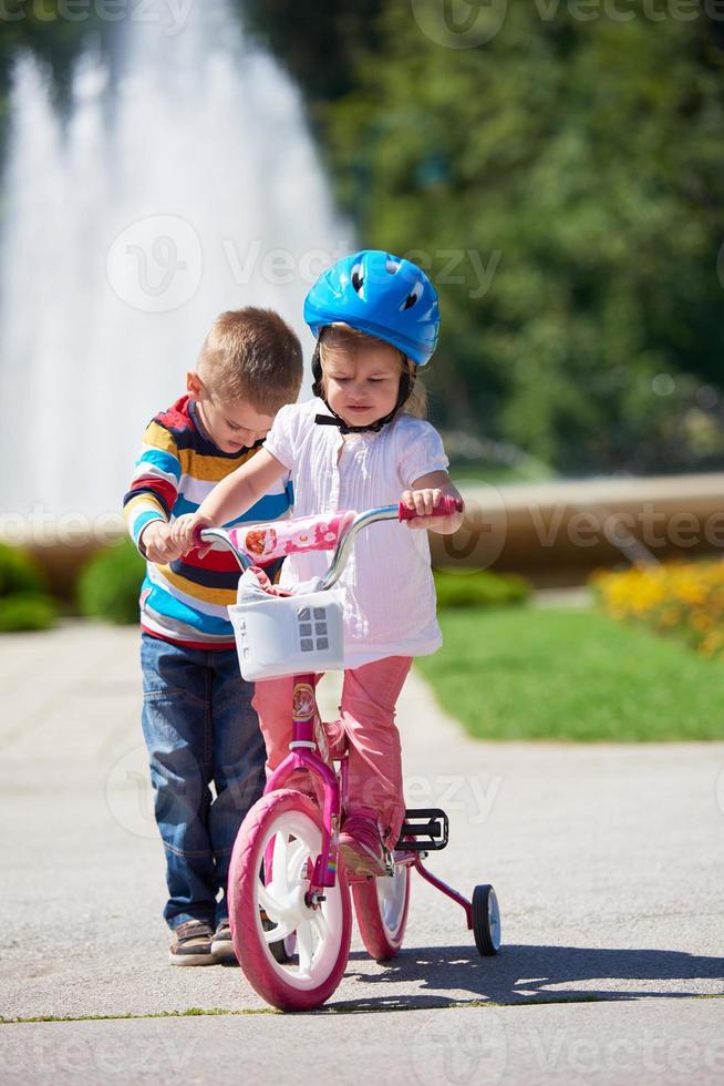 Boy and girl in park learning to ride a bike photo