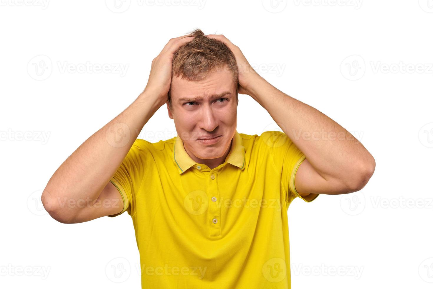 Upset young male in yellow T-shirt clutched at head, forgetful man, isolated on white background photo