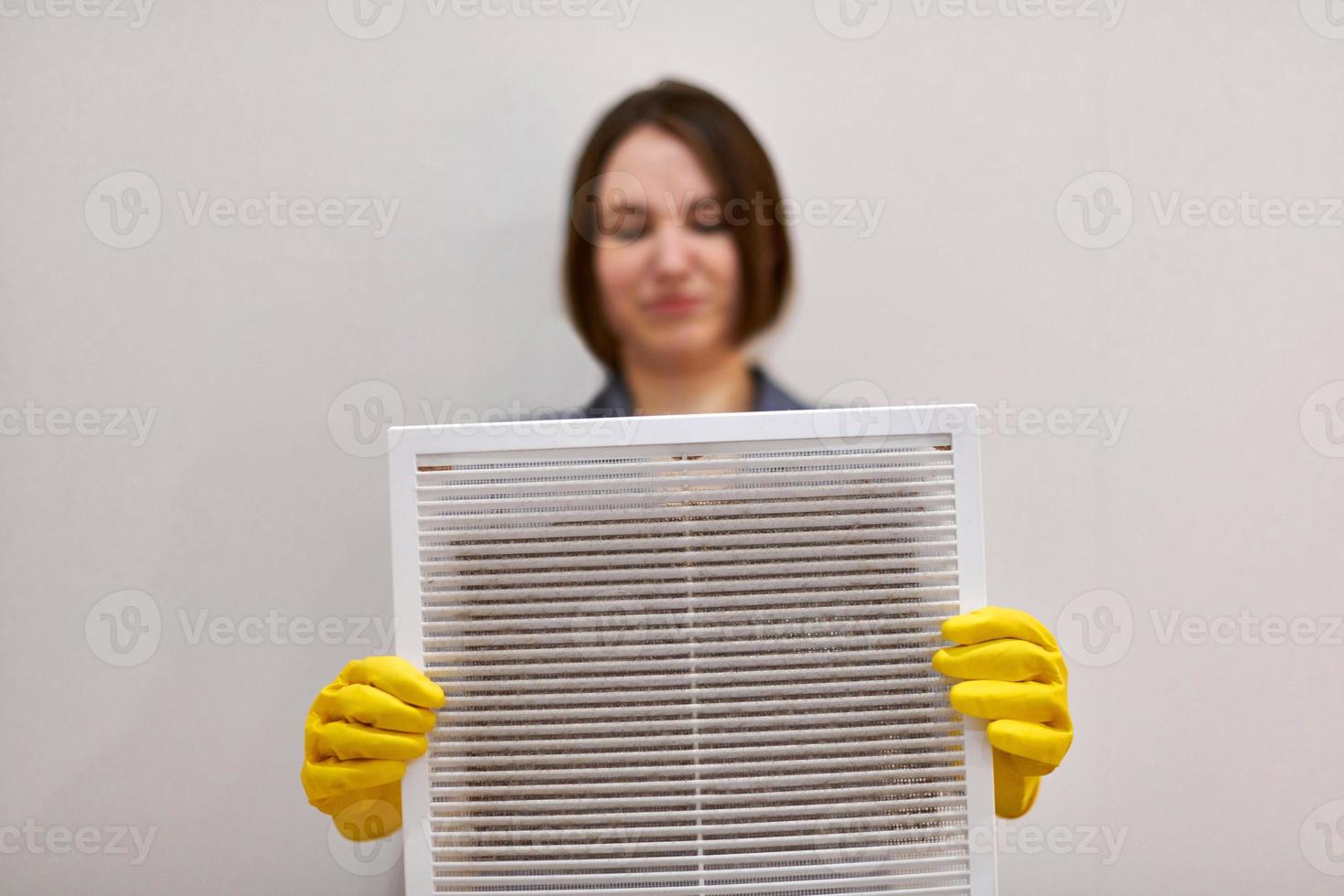 Woman holding dirty and dusty ventilation grille, disgusted photo