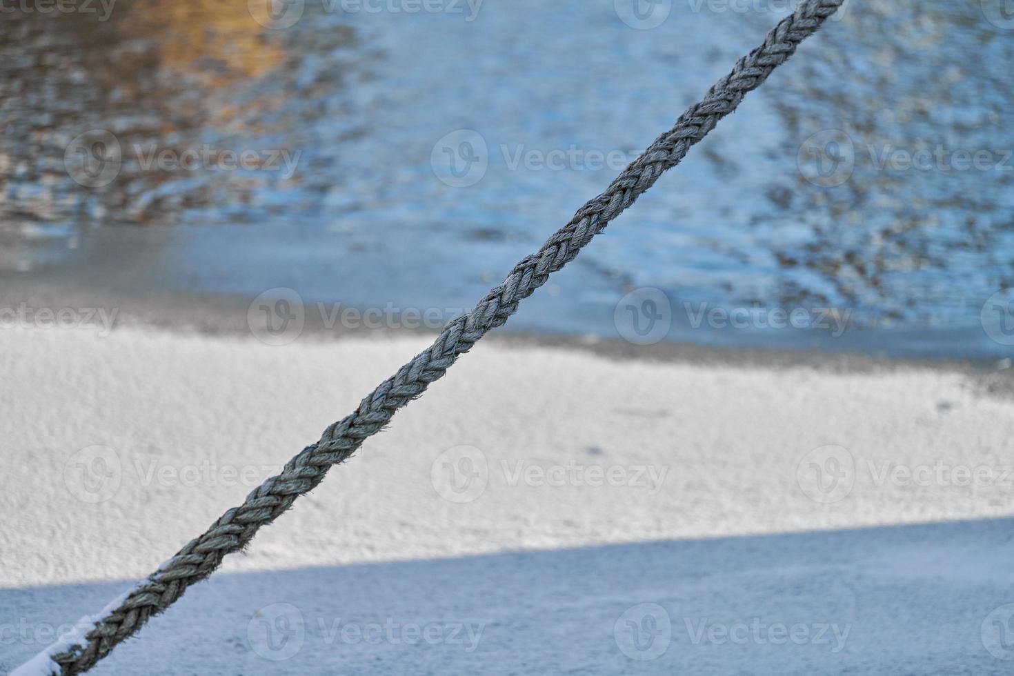 Rope on background of sea water in winter, close up photo