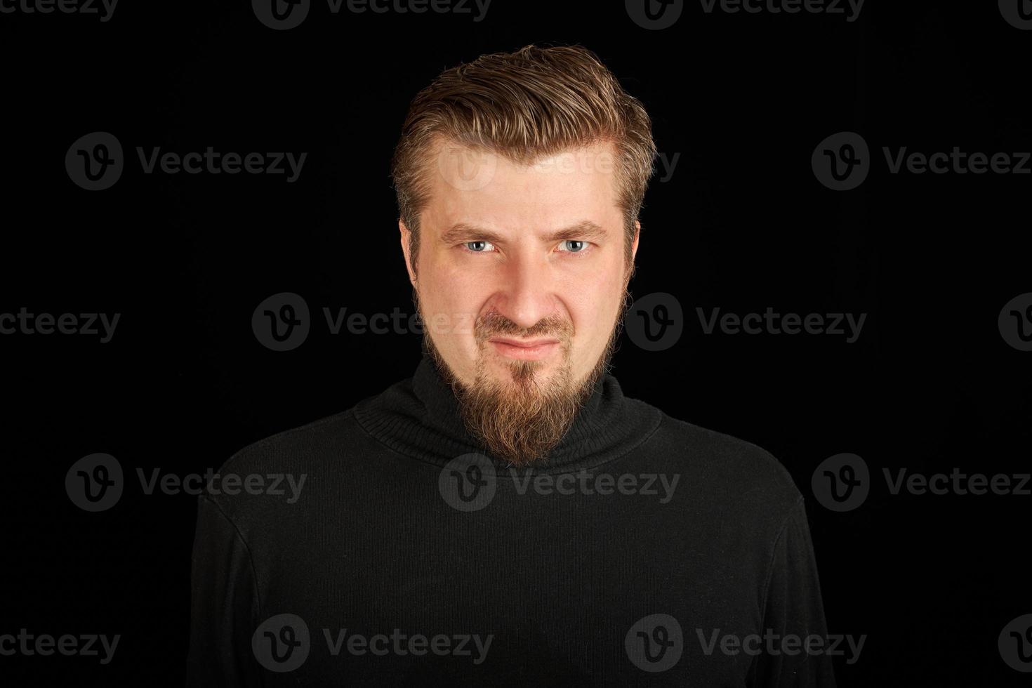 Tense bearded young guy in black polo neck sweater. photo