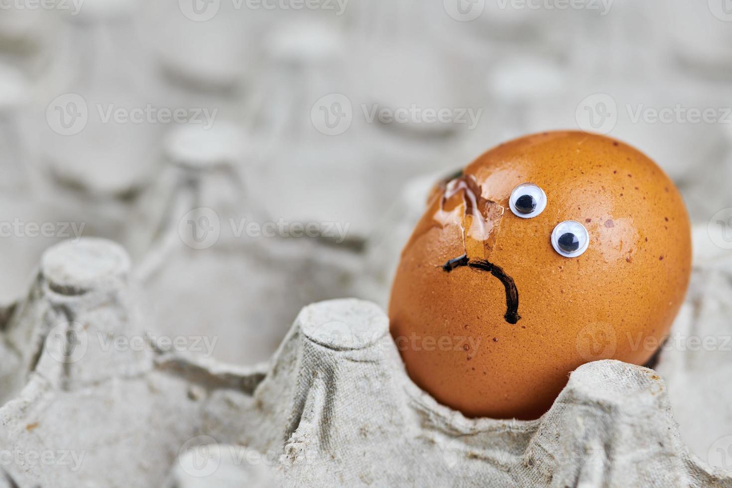 Sad cracked egg in paper egg tray photo