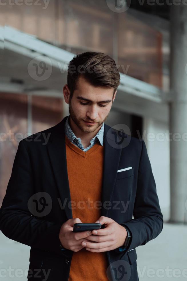 businessman architect using a smartphone while overseeing the construction site photo