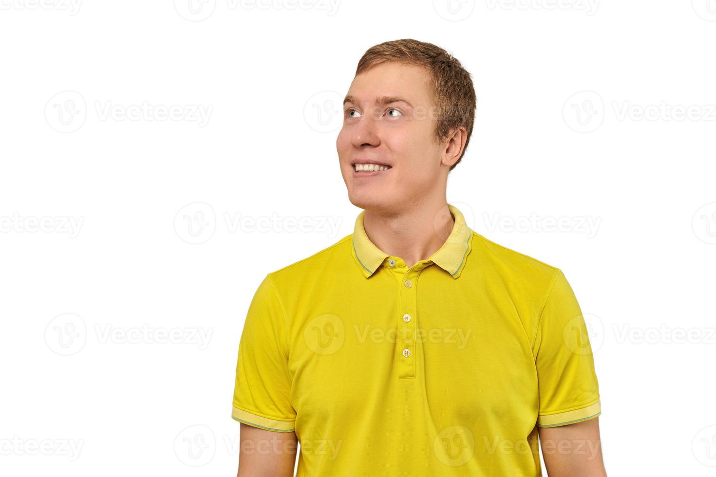 Retrato de hombre joven divertido en camiseta amarilla mirando a la derecha aislado sobre fondo blanco. foto