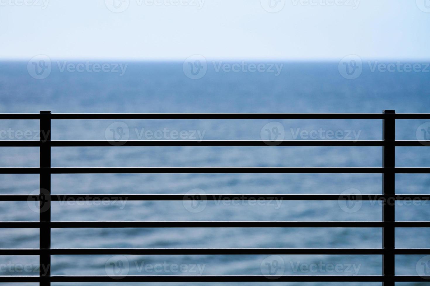 Fencing on observation deck, blue sea background, protection of tourists from falling off cliff photo