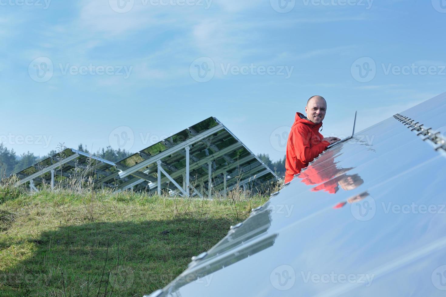 engineer using laptop at solar panels plant field photo