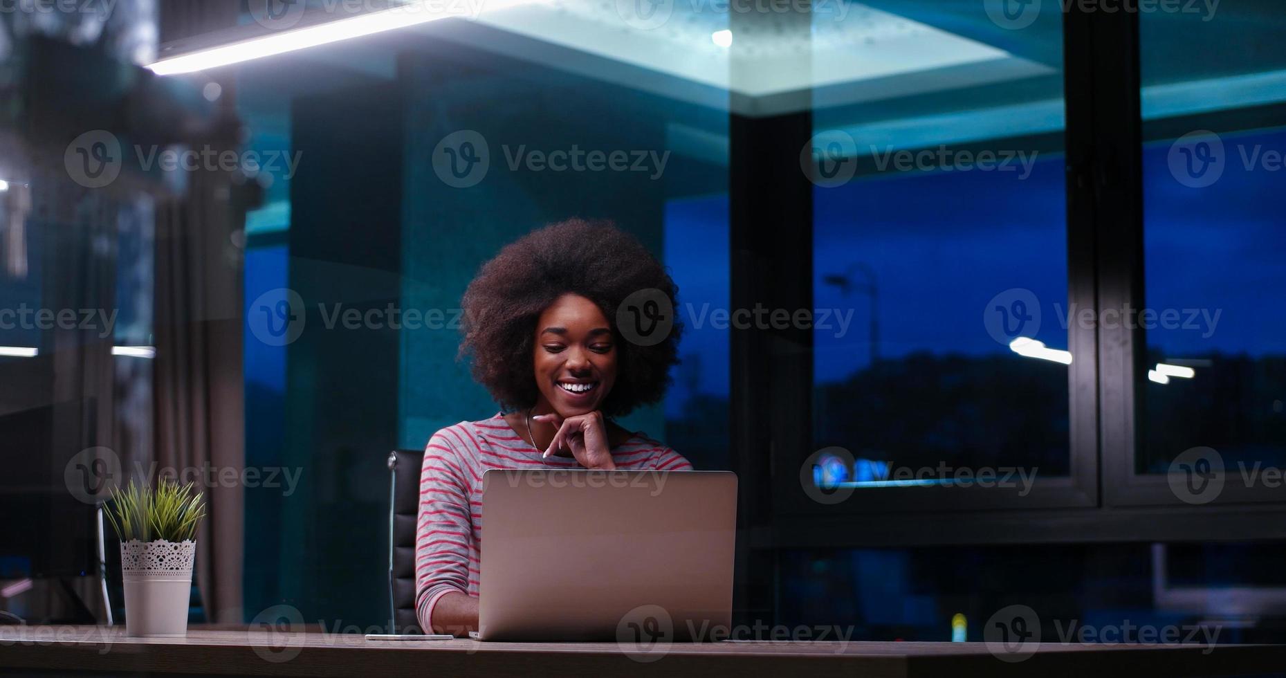 black businesswoman using a laptop in night startup office photo